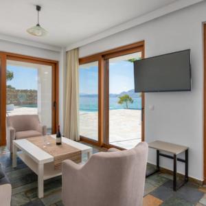 a living room with a television and a table and chairs at Arte Pefki Beachfront Suites in Pefki