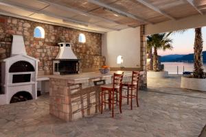 an outdoor kitchen with a fireplace and stools at Arte Pefki Beachfront Suites in Pefki