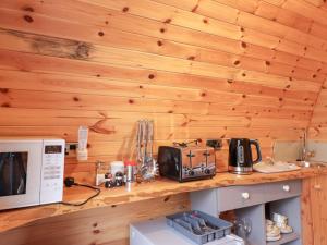 a kitchen with wooden walls and a counter with a microwave at Pod 1 in Belladrum +6 photos