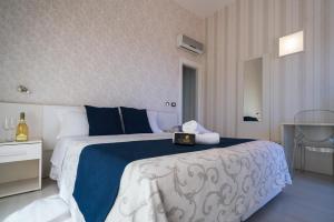 a bedroom with a large bed with a blue and white blanket at Hotel Baia Azzurra in Taormina
