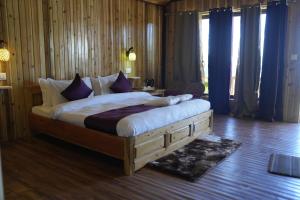 a bedroom with a large bed with purple pillows at Amarvi Hotel & Resort in Kalimpong
