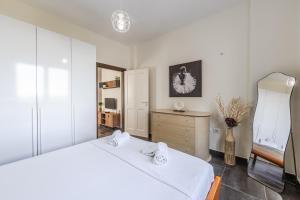 a white bedroom with two beds and a dresser at The Seabreeze Apartment by PikHost in Lalzit Bay