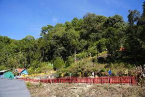 a red fence on top of a hill with trees at Amarvi Hotel & Resort in Kalimpong +3 photos