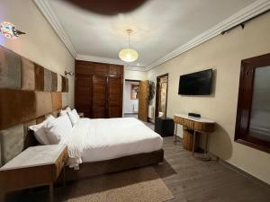 a bedroom with a bed and a desk and a television at L'empreinte D'ifrane in Ifrane