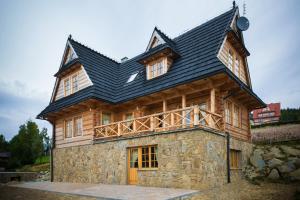 ein großes Holzhaus mit schwarzem Dach in der Unterkunft Smrekowy Dworek in Kościelisko