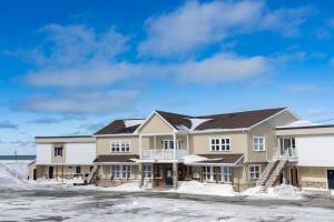 a large house with snow on the ground at Le Gaspesiana in Sainte-Flavie