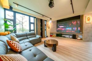 a living room with a couch and a flat screen tv at 閒晃趣-包棟民宿-依訂房人數提供房間數 in Ch'i-wu-lao