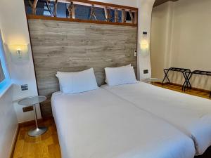 a bedroom with a large white bed with a wooden headboard at RIOSHOUSE Henley in Henley on Thames