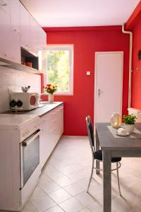 a kitchen with a table and a red wall at Central Park Apartment in Čačak