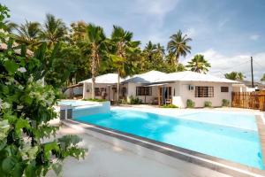 a villa with a swimming pool in front of a house at Seashore Beach hotel and Bungalow in Kumba Urembo