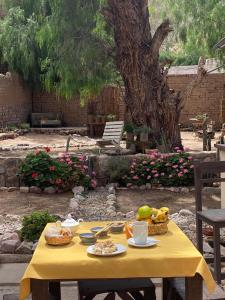 a yellow table with food on it next to a tree at Refugio Caro Cox in Tilcara