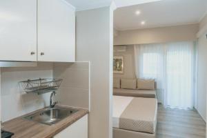 a kitchen with a sink and a bed in a room at Ammos Beach Seaside Luxury Suites Hotel in Olympic Beach
