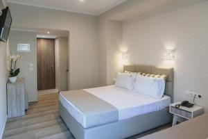 a bedroom with a large white bed with white pillows at Ammos Beach Seaside Luxury Suites Hotel in Olympic Beach