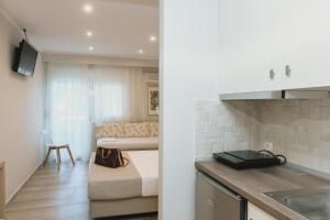a kitchen and a living room with a bed in a room at Ammos Beach Seaside Luxury Suites Hotel in Olympic Beach