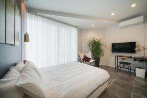 a bedroom with a large white bed and a desk at INFINITY HOTEL -Higawa- in Naha