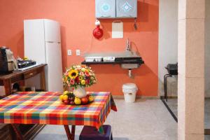 a kitchen with a table with a vase of flowers and fruit at Paraíso Pedra Encantada in Paracuru +15 photos
