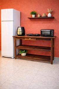 a kitchen with a refrigerator and a table with a microwave at Paraíso Pedra Encantada in Paracuru