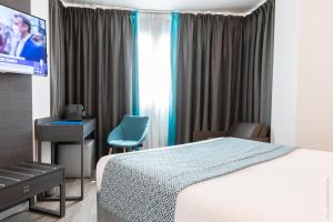 a hotel room with a bed and a tv at Hôtel Versailles Chantiers in Versailles