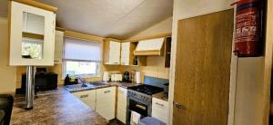 a small kitchen with white cabinets and a stove at Caravan in Clacton-on-Sea in Little Clacton