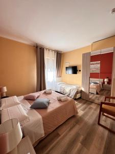 a bedroom with two beds and a television in it at Hotel Urban By Giulia in Pozzolo Formigaro