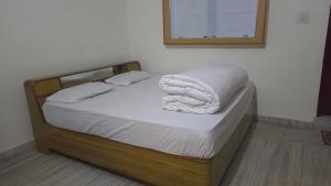 a bed with a wooden frame with a white blanket on it at Hotel SPT Palace Phata in Phata