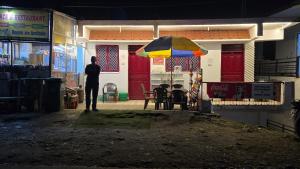 a man standing in front of a building with an umbrella at Hotel SPT Palace Phata in Phata