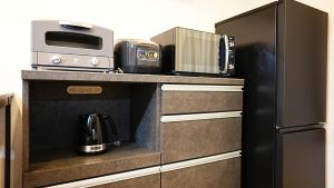 a kitchen with a counter with a microwave and a refrigerator at Cloud House Sapporo in Sapporo
