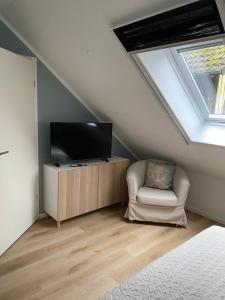 a attic room with a tv and a chair at Ferienwohnung Frers in Rallenbüschen