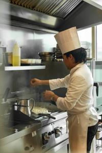 a woman in a kitchen preparing food on a stove at St Helens Hotel, Dublin in Stillorgan