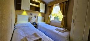 two beds in a small room with a window at Caravan in Clacton-on-Sea in Little Clacton