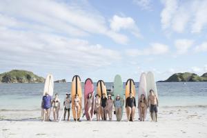 a group of people standing in front of surfboards on the beach at Porter Boutique Hotel & Lifestyle in Kuta Lombok