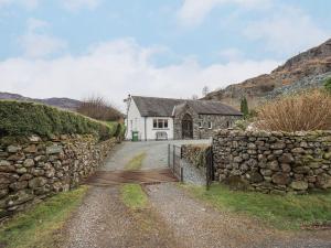 an old house with a stone wall next to a road at Thrang View in Ambleside