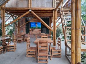 ein Restaurant mit Holztischen und -stühlen und einem Bildschirm in der Unterkunft HostalElCascolManabiPuertolopez in Puerto López