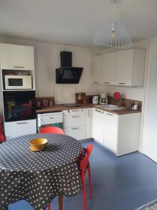 a kitchen with a table and a kitchen with white cabinets at Appartement avec balcon et vue sur les montagnes in Bielle