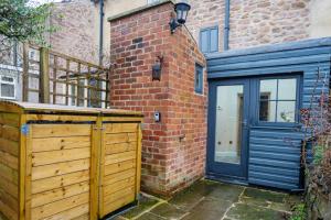 a house with a wooden gate and a brick building at Mill Workers Cottage in Cromford