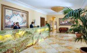 dos personas sentadas en un mostrador en el vestíbulo del hotel en Grand Hotel Due Golfi, en SantʼAgata sui Due Golfi