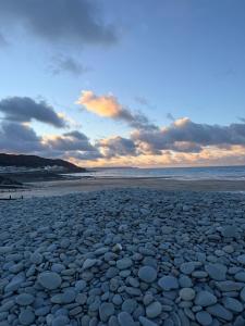 a beach with a large amount of rocks on it at Rambler's Rest Boutique Apartment in Westward Ho