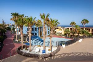 a resort with a swimming pool with palm trees at Occidental Jandía Playa in Morro del Jable
