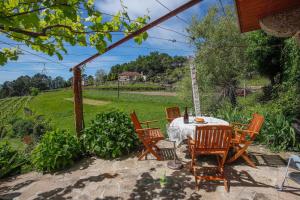 a patio with a table and chairs and a field at Casa Cabreiros de Baixo in Melgaço