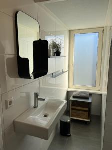 a bathroom with a sink and a mirror and a window at Appartement met uitzicht over de Wadden Zee in Oost-Vlieland