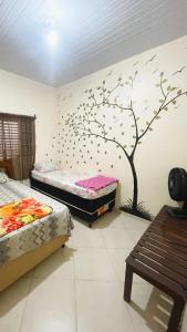 a bedroom with two beds and a tree on the wall at Conexão oito in Alto Paraíso de Goiás