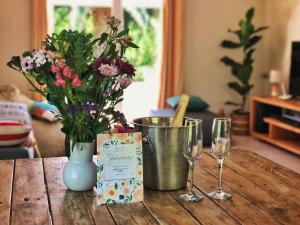 a table with a vase and two glasses of wine at Swannie Creek private nature retreat with hot tub and fireplace in Grabouw