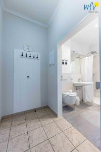 a white bathroom with a toilet and a sink at Haus am Hövt - Ferienwohnung 1 in Göhren +32 photos