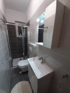 a white bathroom with a toilet and a sink at Apartments Nela in Jelsa