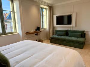 a bedroom with a bed and a couch and a tv at Logis Hôtel Maison Turenne in Martel
