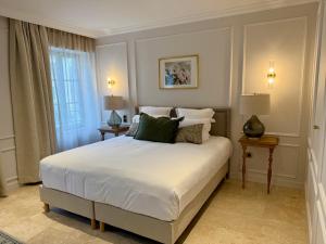 a bedroom with a white bed with two tables and a window at Logis Hôtel Maison Turenne in Martel