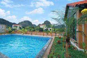 a swimming pool in a resort with mountains in the background at Trang An Green Retreat Homestay in Ninh Binh