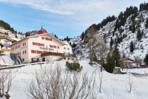 a large building on a snowy hill with a mountain at Berghaus Stuben Arlberg mit Sauna Panoramablick und Nähe zur Piste in Stuben am Arlberg