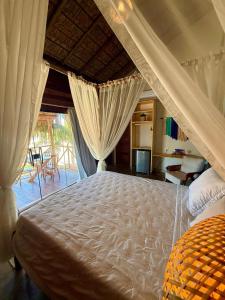 a bedroom with a large white bed with curtains at Pousada Villa Velejo in Grossos