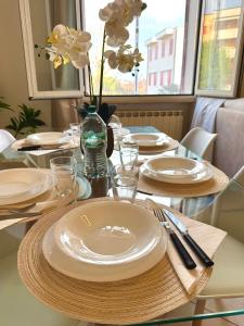 a table with white plates and a vase with flowers at Appartamento Camelia vista mare in Lido Adriano